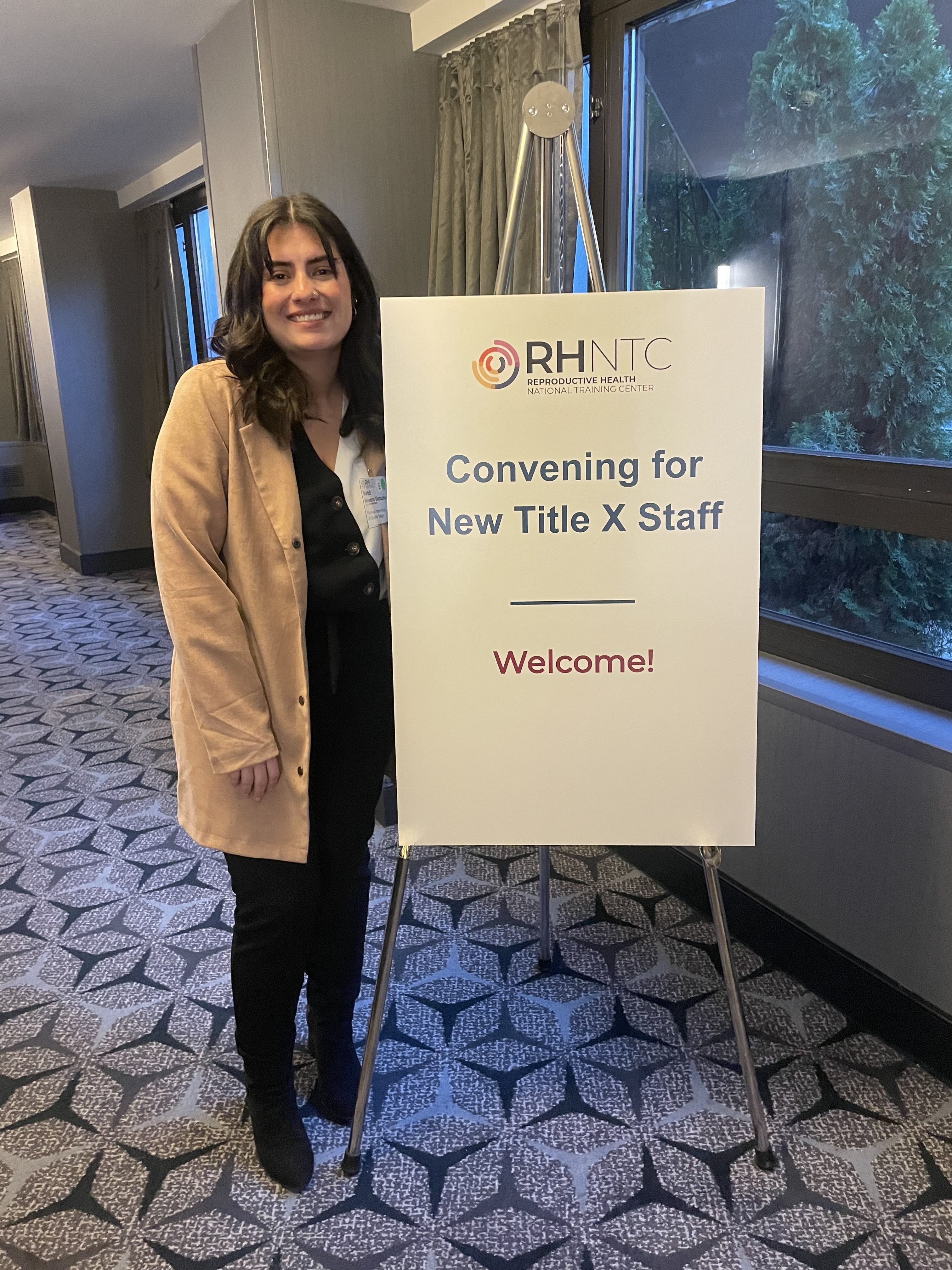 Image of Metzli Navarro from Planned Parenthood of Texas, standing next to an RHNTC welcome sign for the Title X Convening